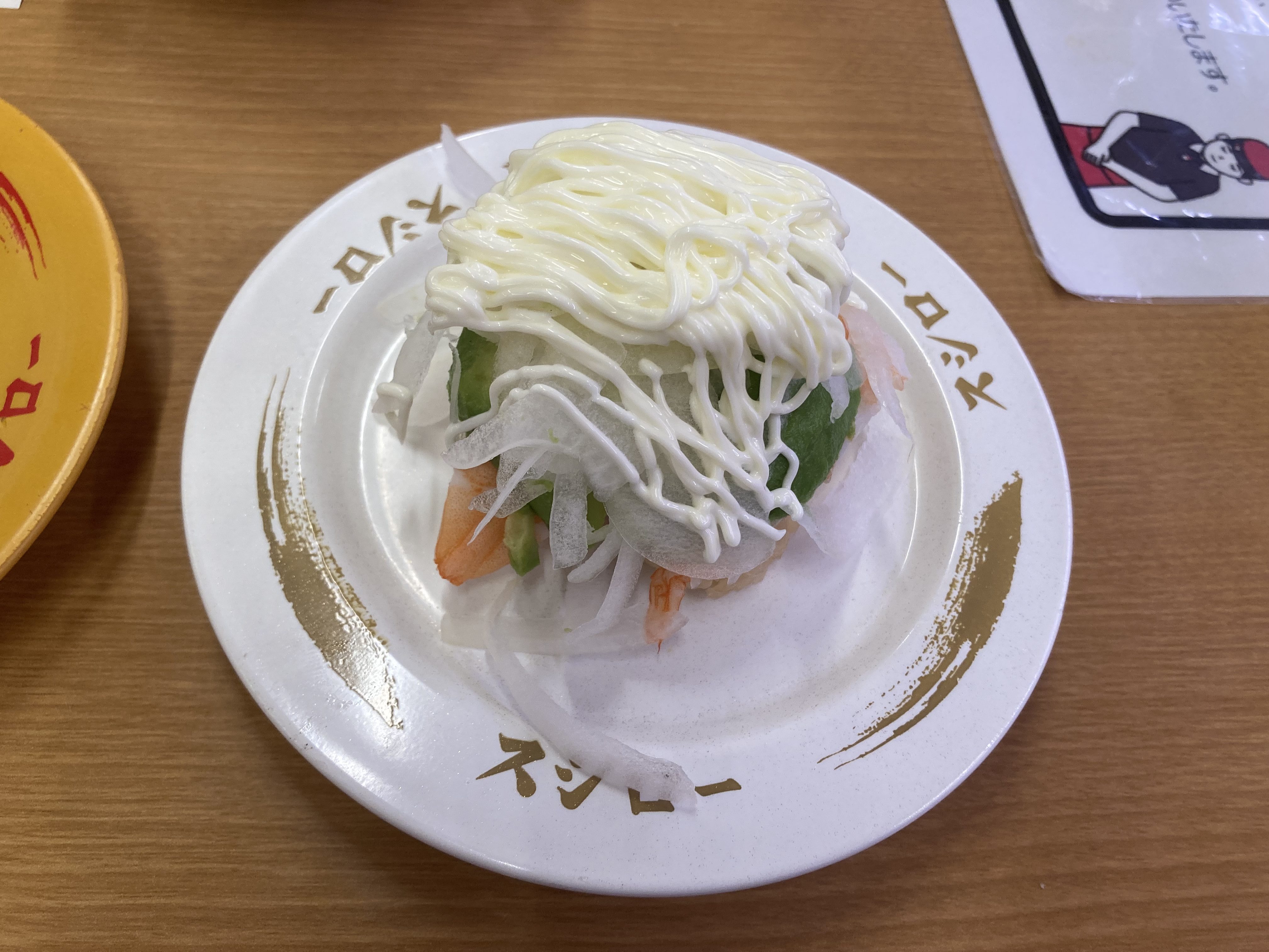 寿司プレートに盛り付けられたエビと野菜の寿司、上にマヨネーズがかかっている