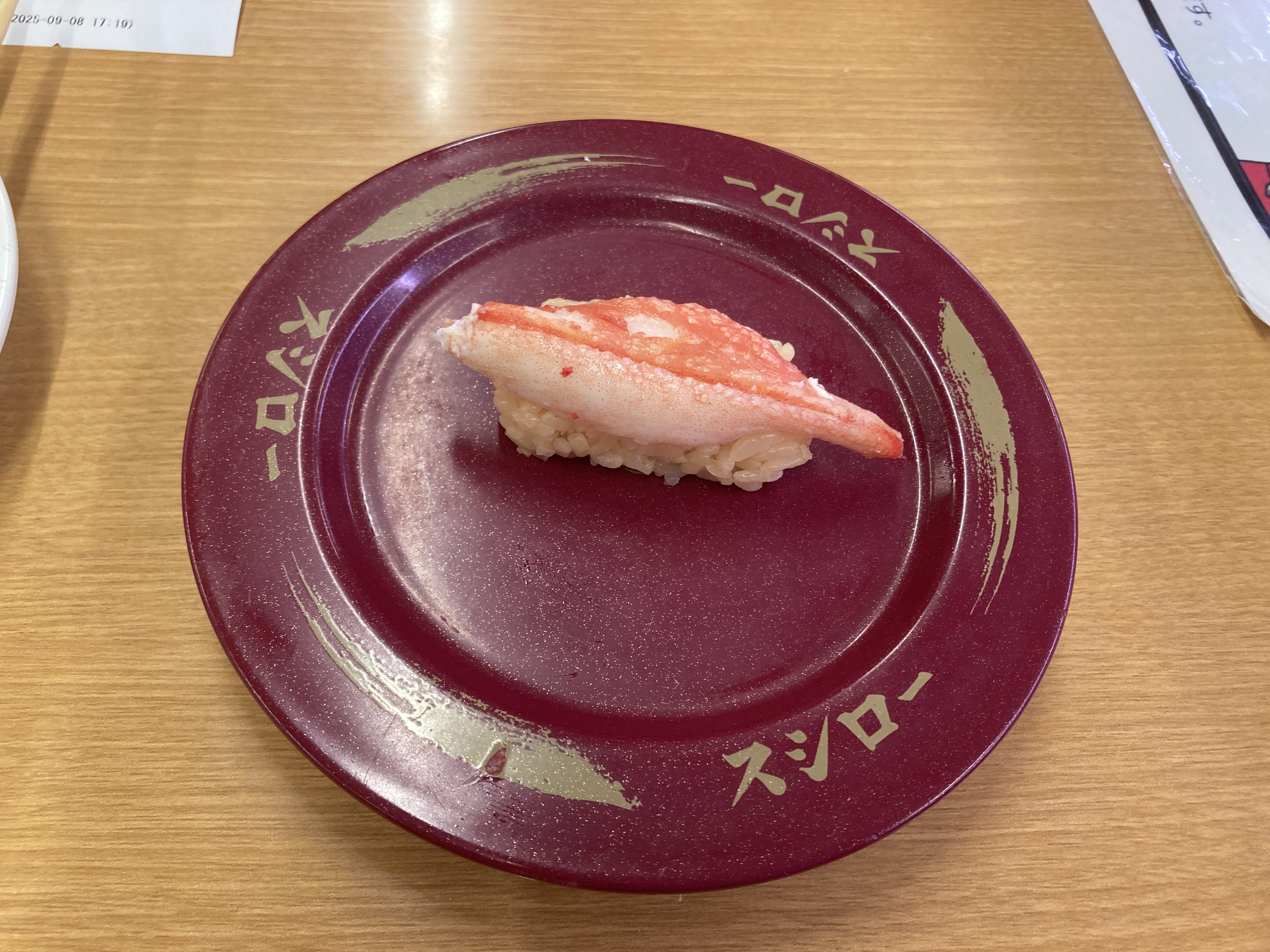 一貫のズワイ蟹寿司が赤い皿に盛り付けられている